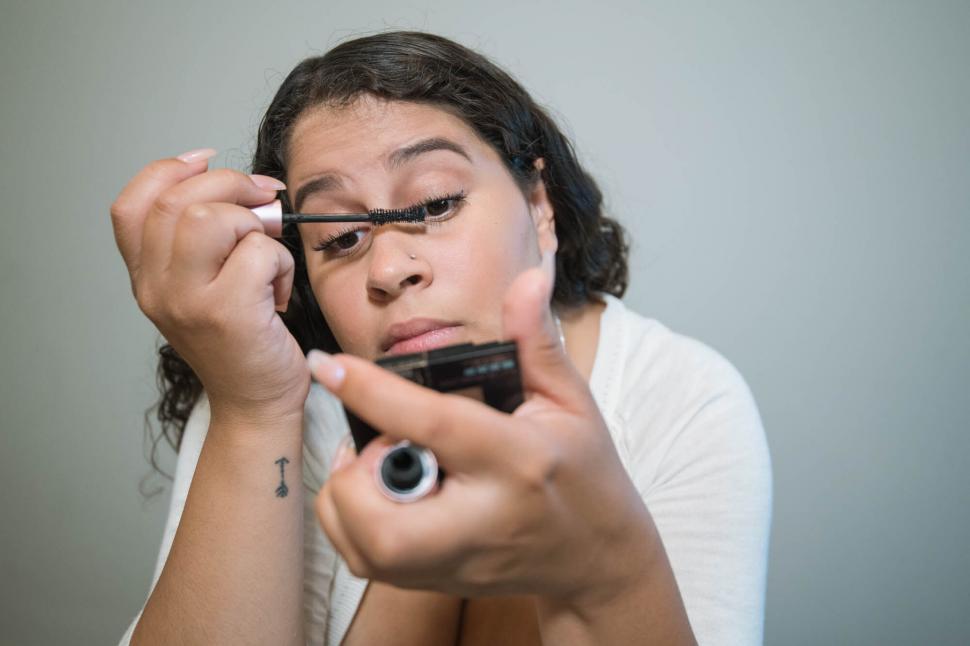 Free Image of Woman applying mascara in front of mirror 