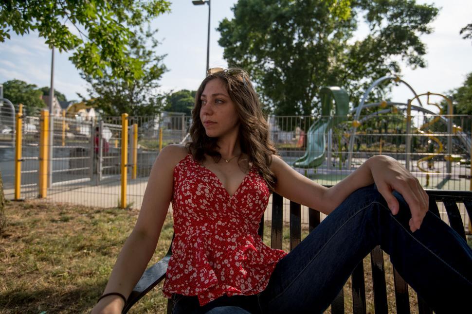 Free Image of Casual woman sitting on park bench 