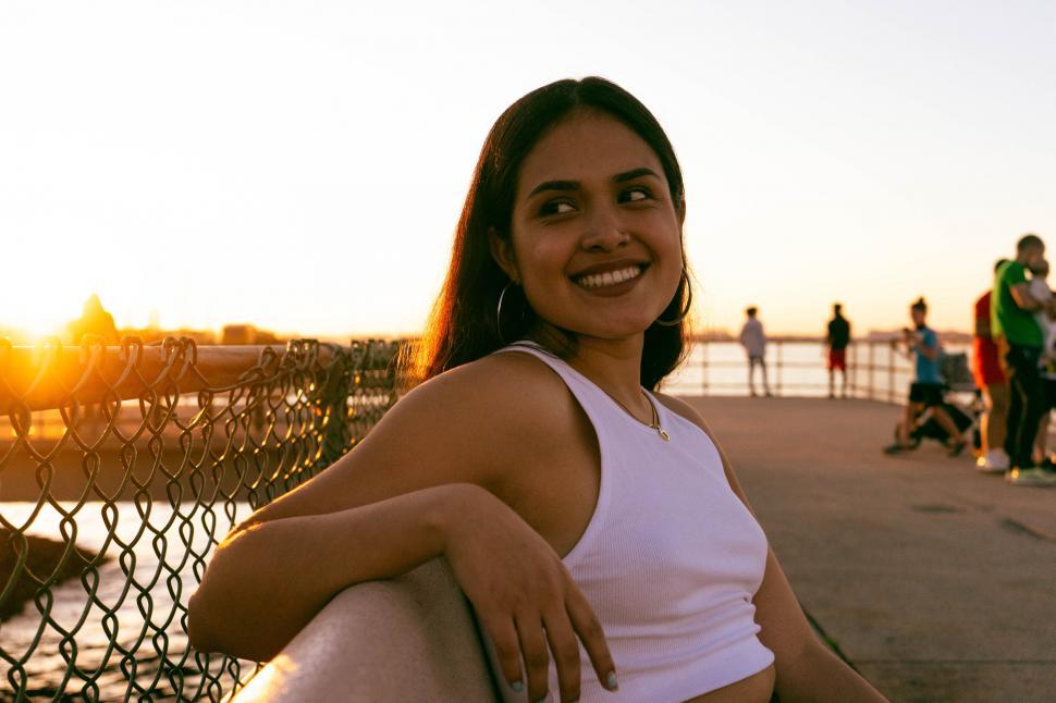 Free Image of Woman smiling at sunset by water 