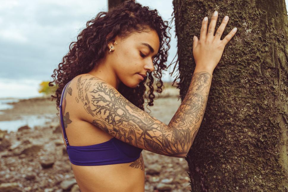 Free Image of Woman hugging a tree with detailed tattoos 