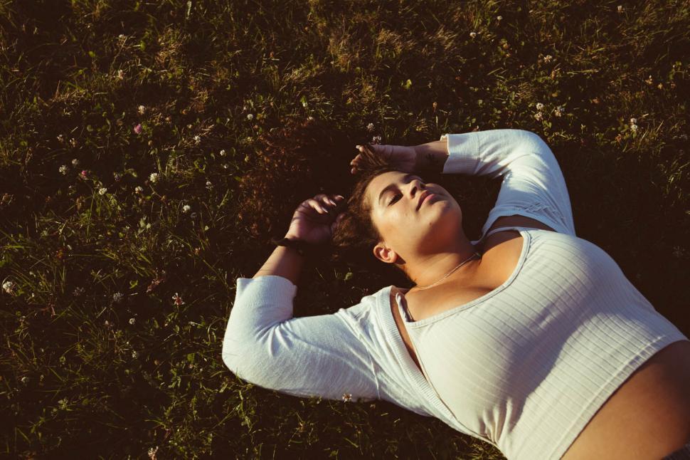 Free Image of Woman relaxing in grass during sundown 