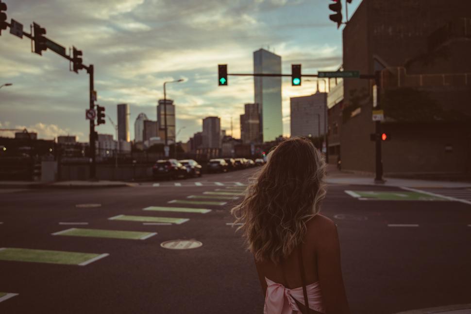 Free Image of Young woman walking towards sunset in city 