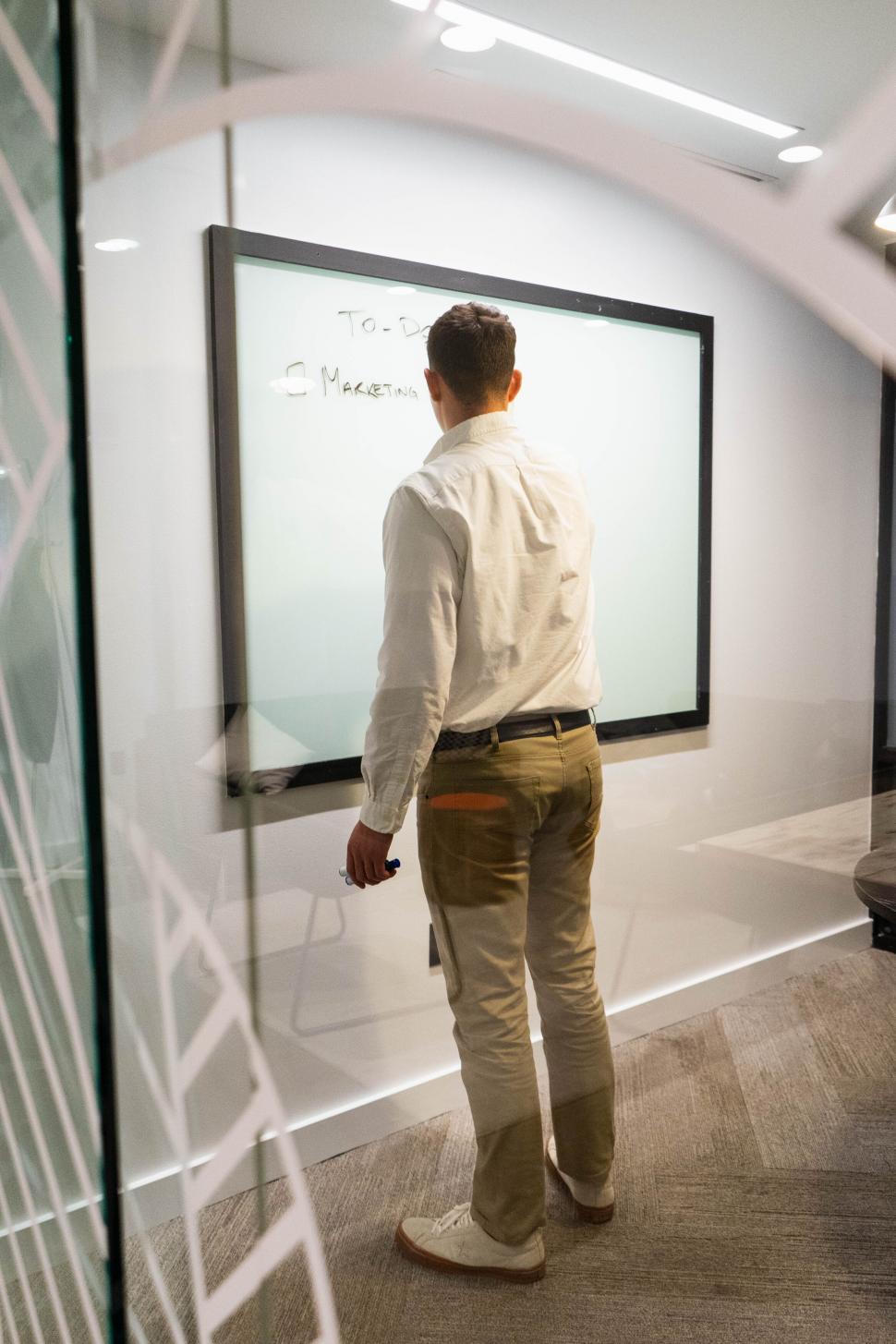 Free Image of Man writing on whiteboard in office 