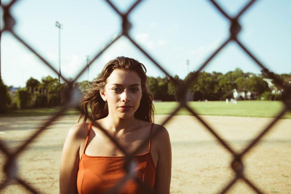 Free Image of Woman behind chain link fence looking at camera 