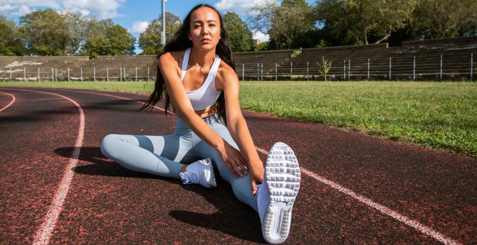 Free Image of Athlete stretching on a running track 