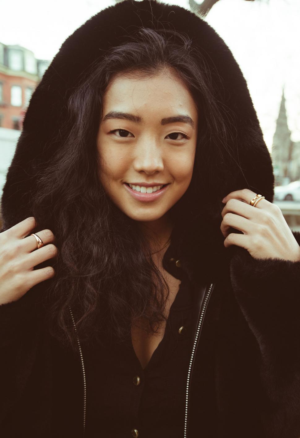 Free Image of Asian woman smiling in hooded fur coat 