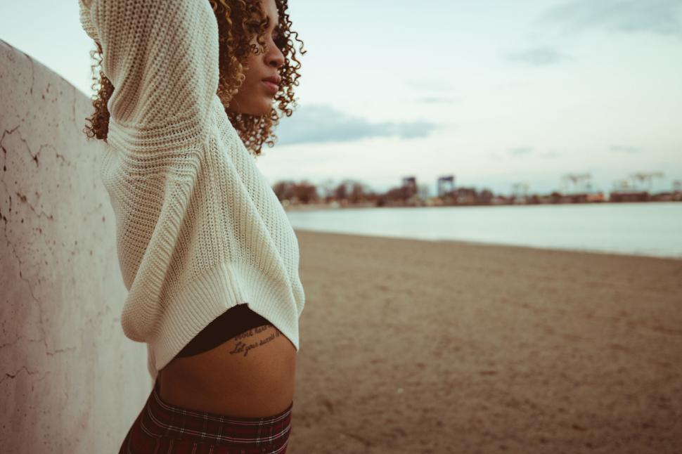 Free Image of Woman leaning on a wall at the beach 
