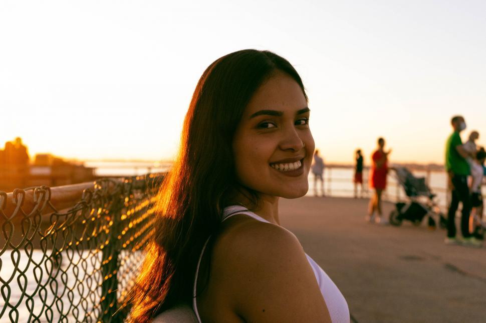 Free Image of Smiling woman at golden hour by water 