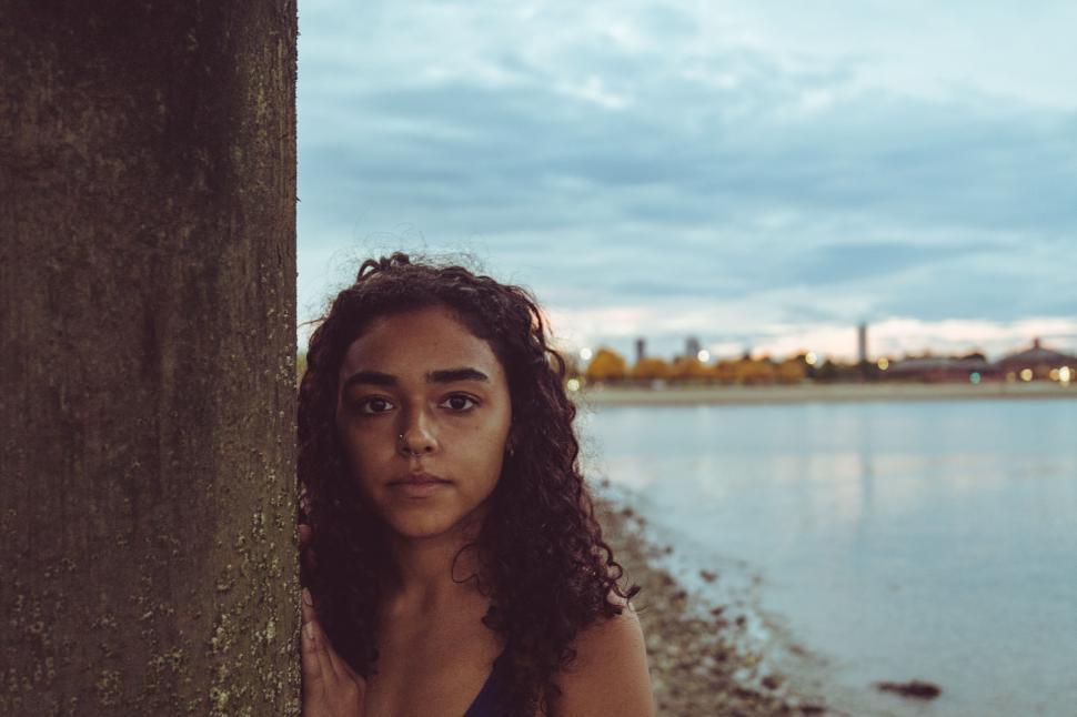 Free Image of Young woman by the waterside at dusk 