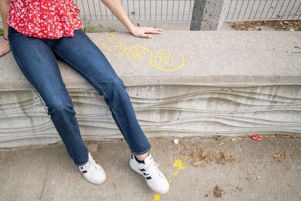 Free Image of Woman sitting with chalk drawings on curb 
