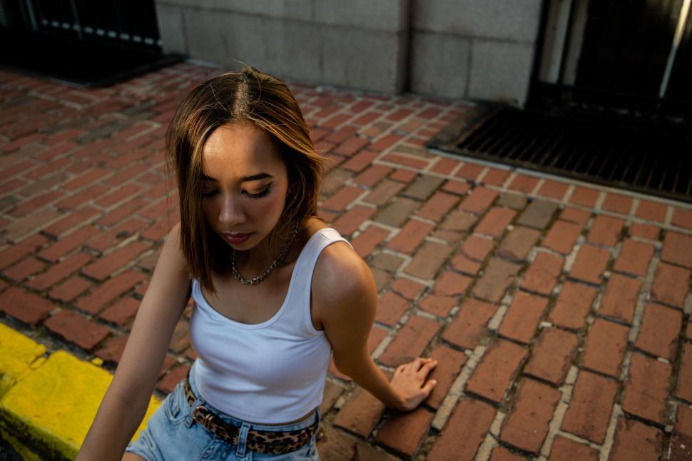 Free Image of Woman crouching on brick pavement 