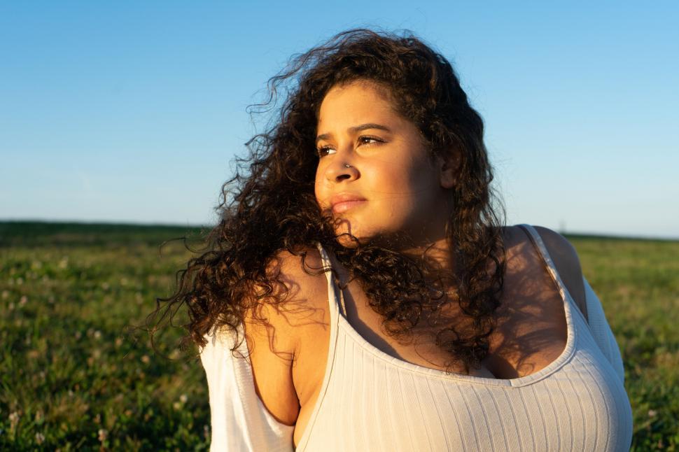 Free Image of Curly-haired woman in field at sunset 