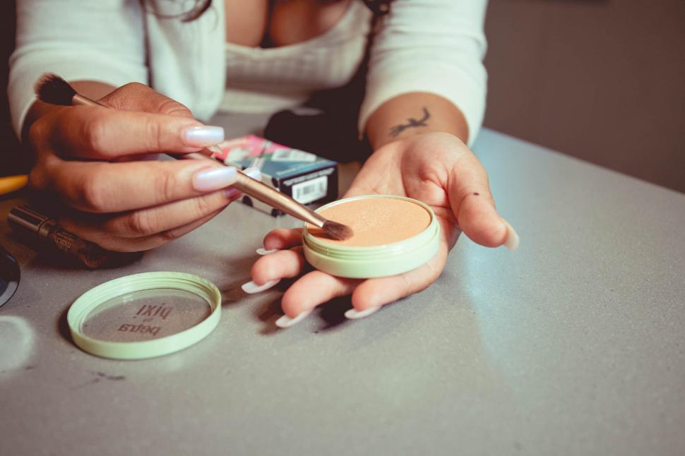Free Image of Applying makeup with brush and compact 