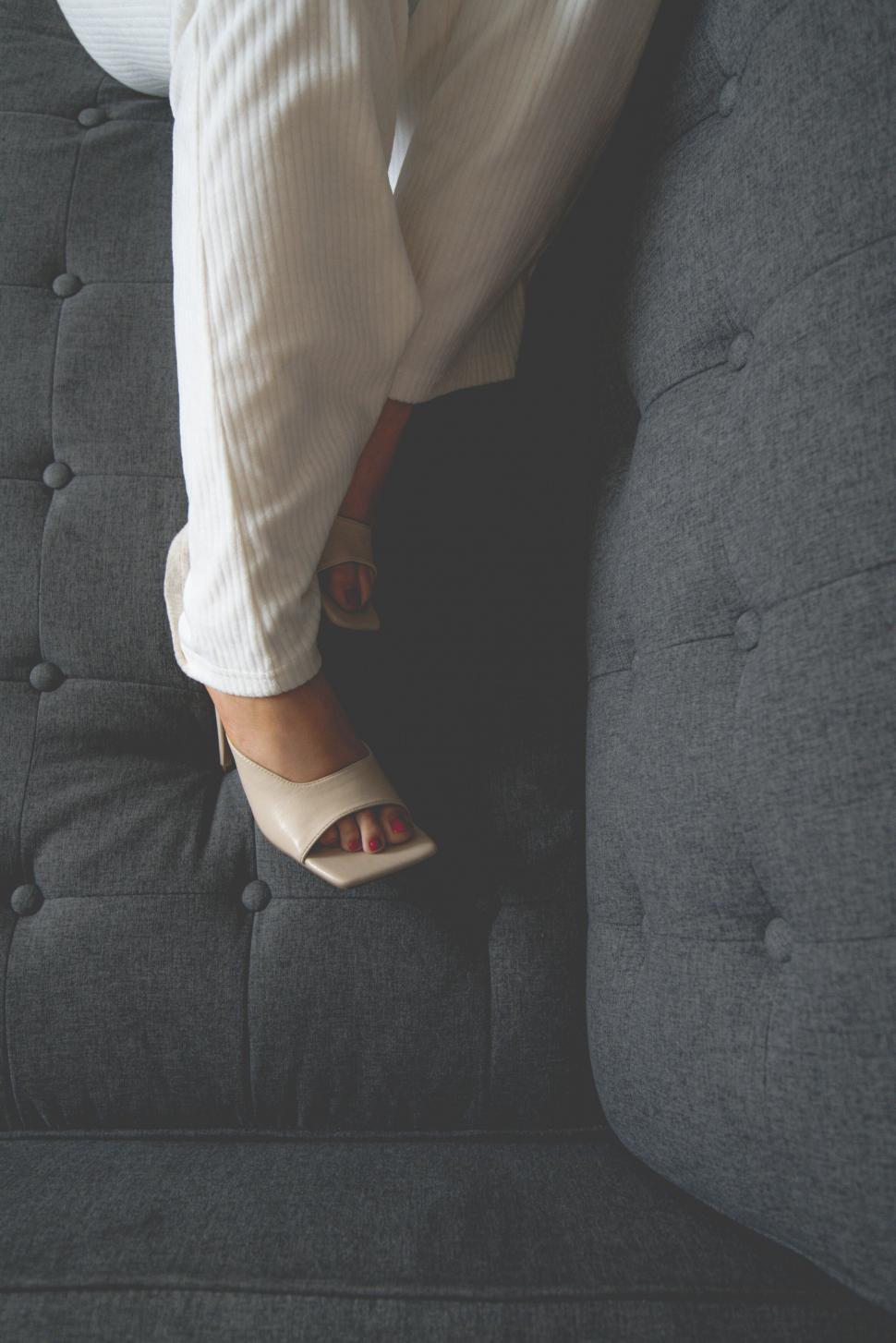 Free Image of Woman s legs on a grey modern couch 