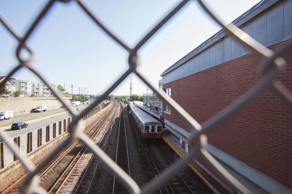 Free Image of View of a train through a chain-link fence 