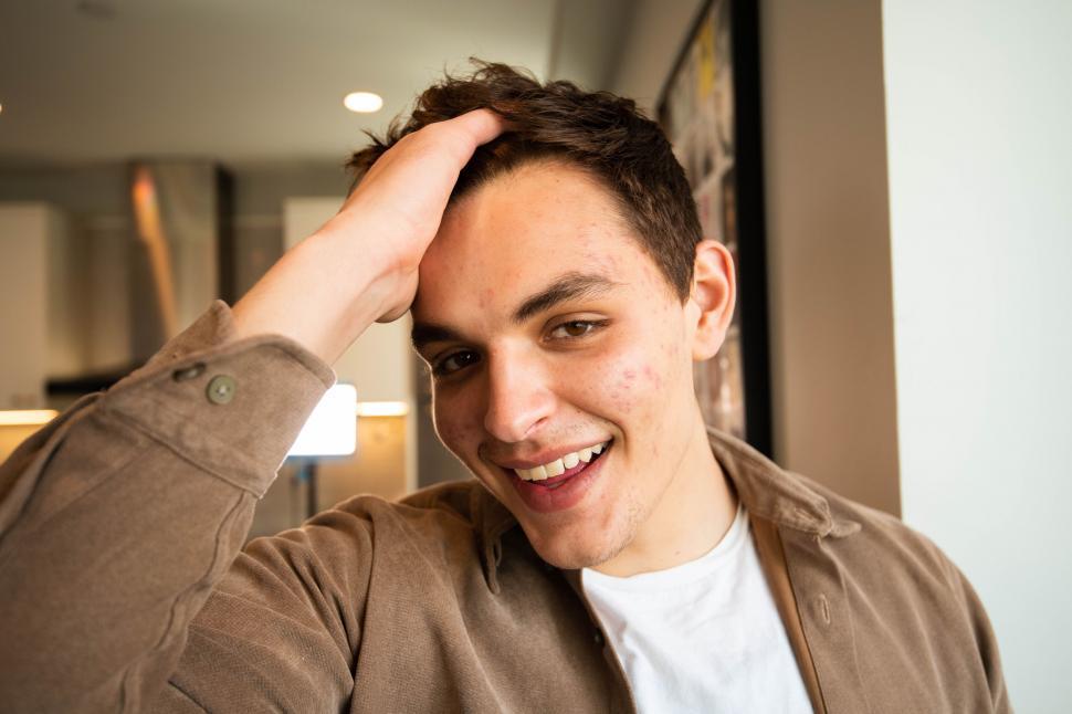 Free Image of Smiling young man with hand on head 