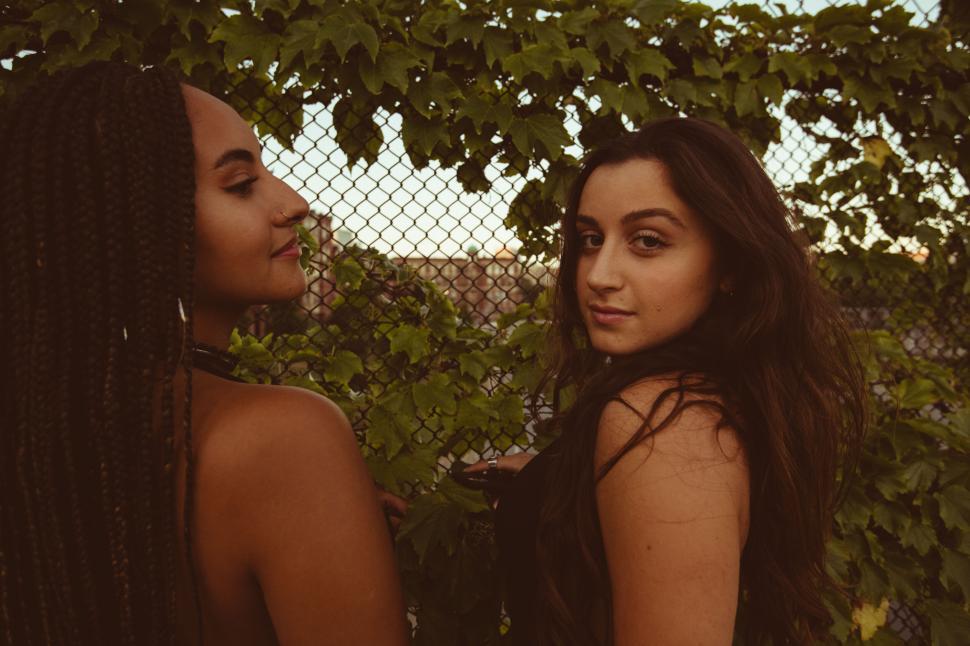 Free Image of Two friends leaning against a vine wall 