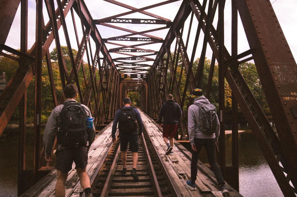 Free Image of Group walking on a rustic railroad bridge 