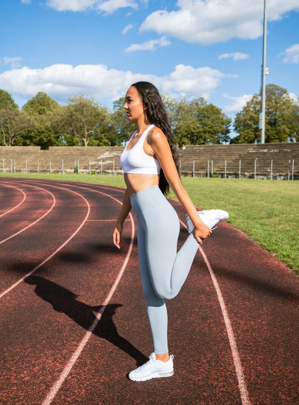 Free Image of Athlete stretching on a sunny track field 