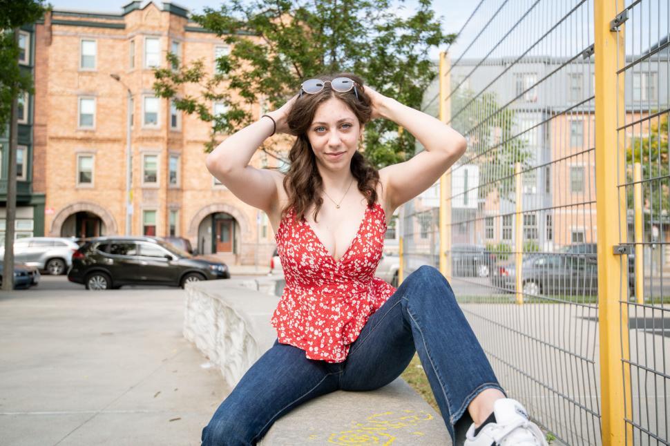 Free Image of Woman sitting on stone ledge in urban setting 