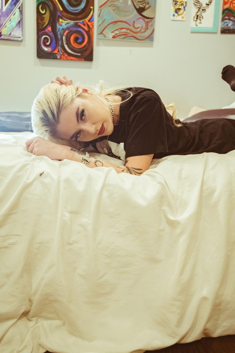 Free Image of Woman lying on a bed gazing at camera 