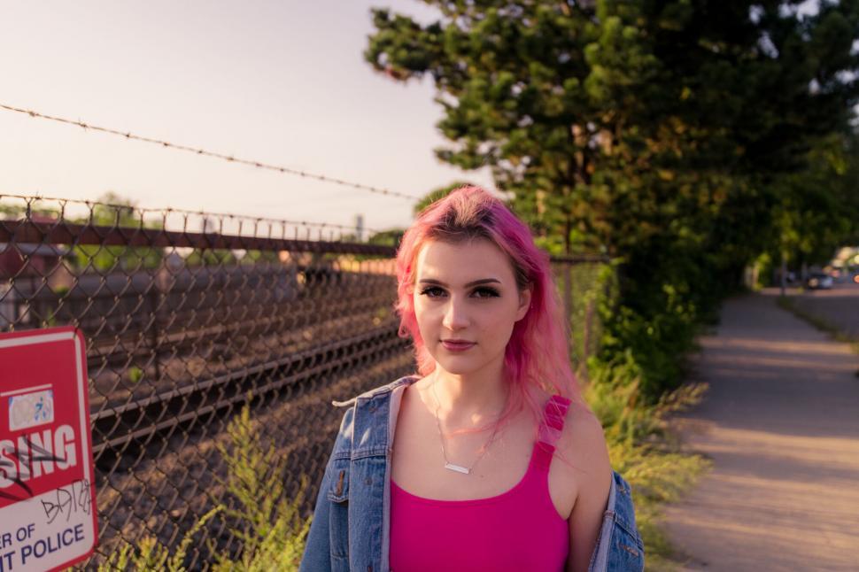 Free Image of Pink-haired woman standing near train tracks 