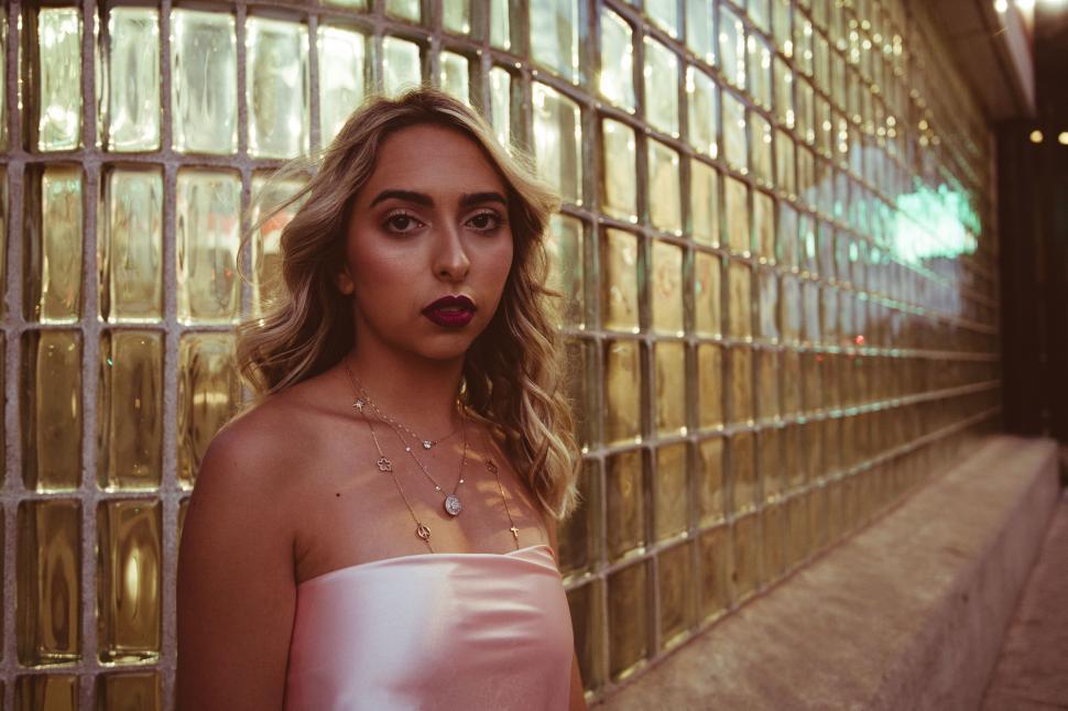 Free Image of Elegant young woman in front of gold wall 