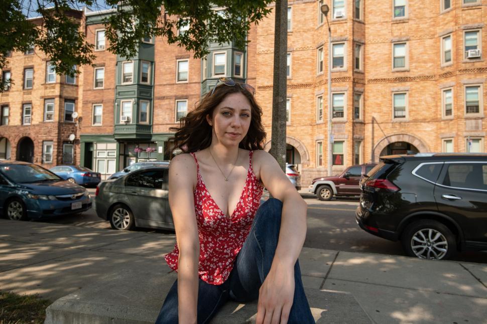 Free Image of Woman sitting casually on a city sidewalk 