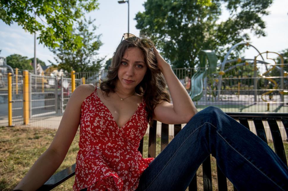 Free Image of Woman relaxing in a park with urban background 