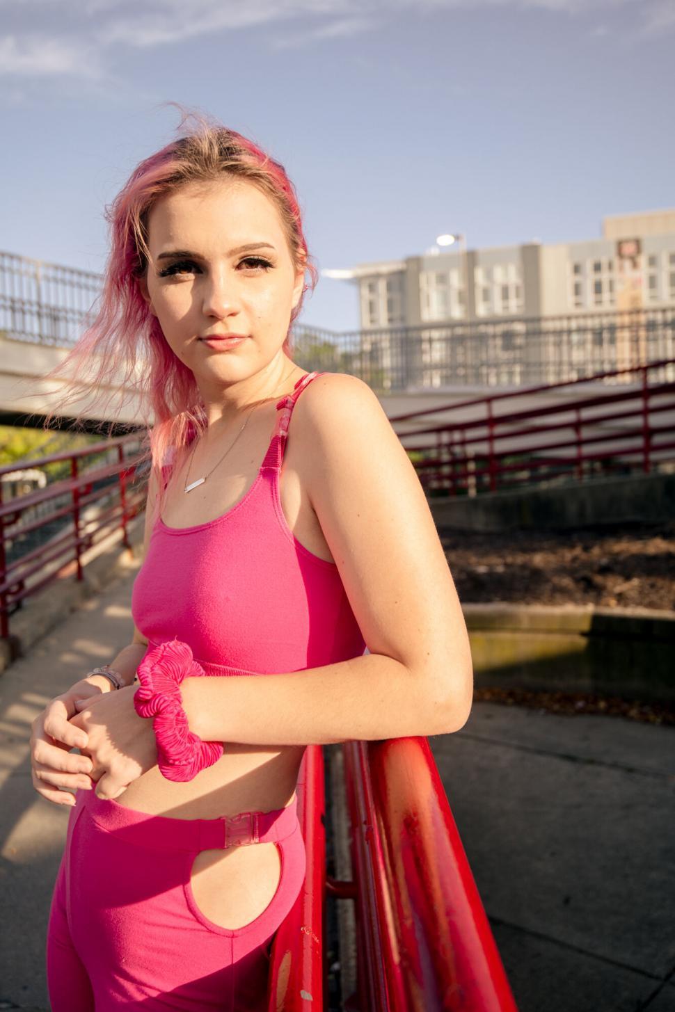 Free Image of Woman in pink outfit leaning on railing 