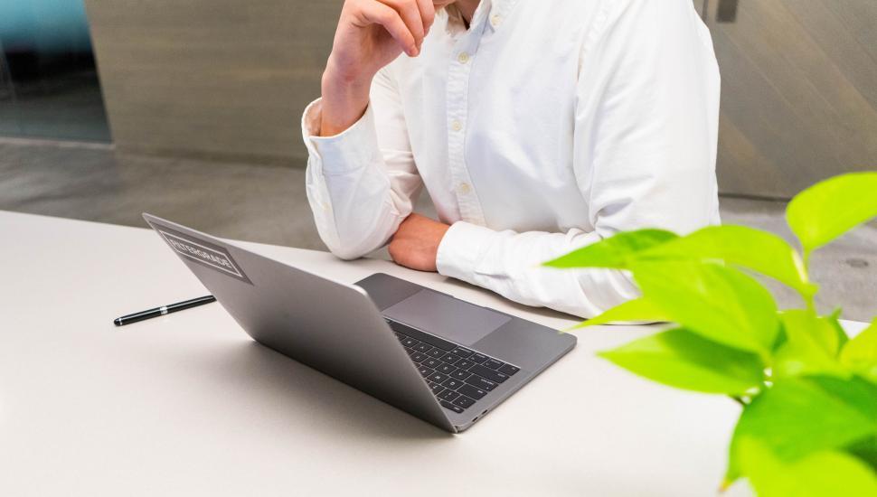 Free Image of Man working on a laptop with a plant nearby 
