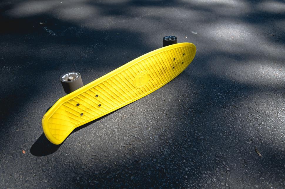 Free Image of Bright yellow skateboard on asphalt 