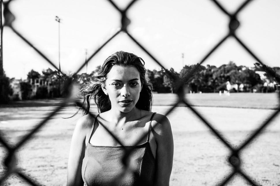 Free Image of Black and white photo of woman behind fence 