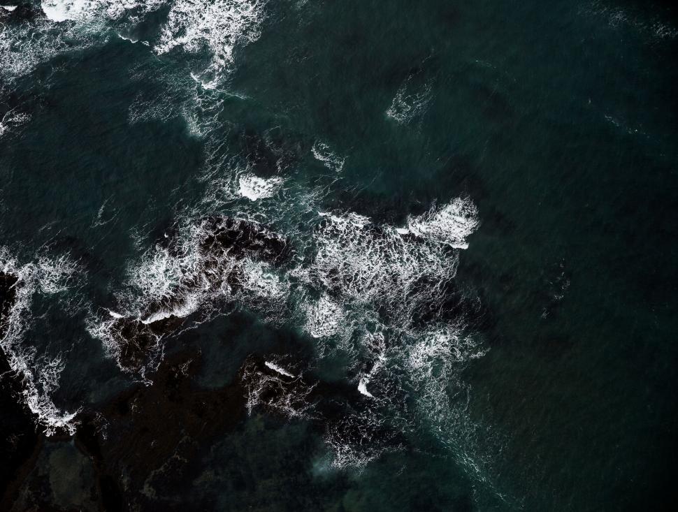 Free Image of Ocean waves clashing against dark rocky shore 