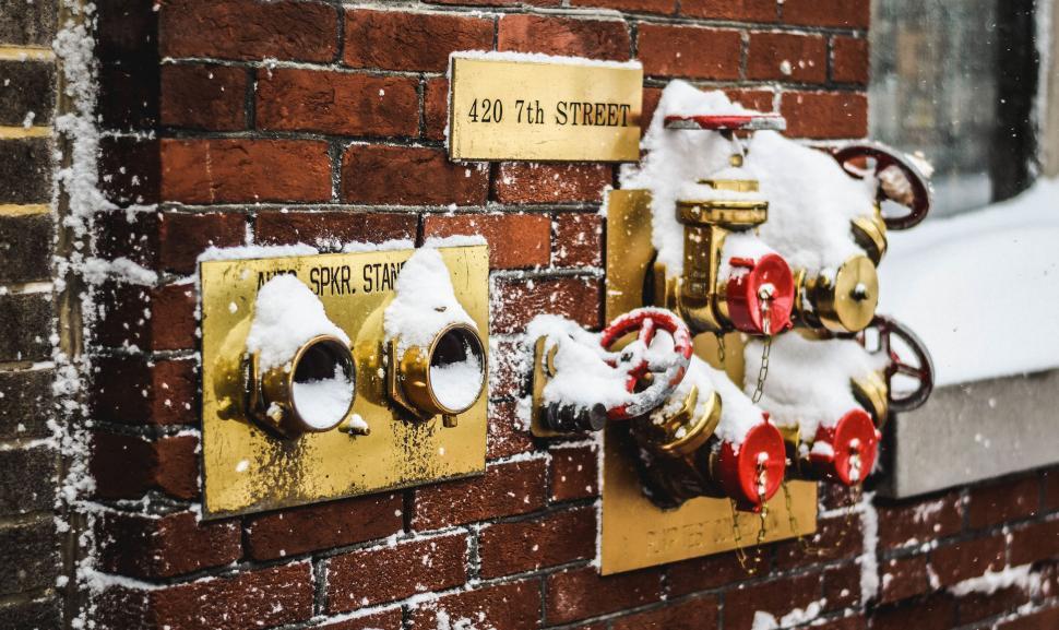 Free Image of Snow-covered fire connection on a brick wall 