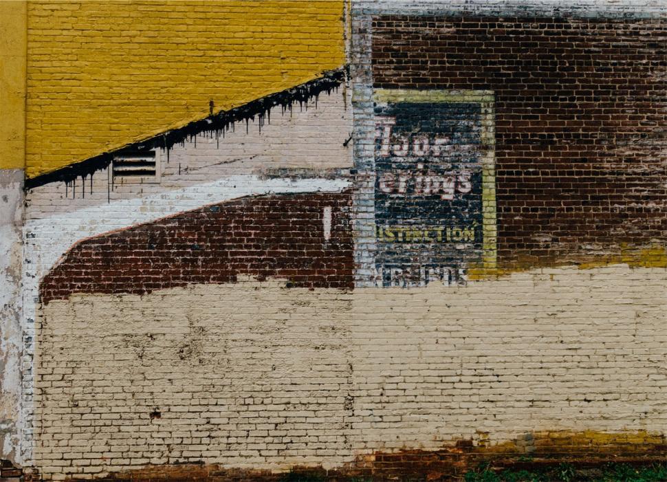Free Image of Faded vintage advertisement on a brick wall 