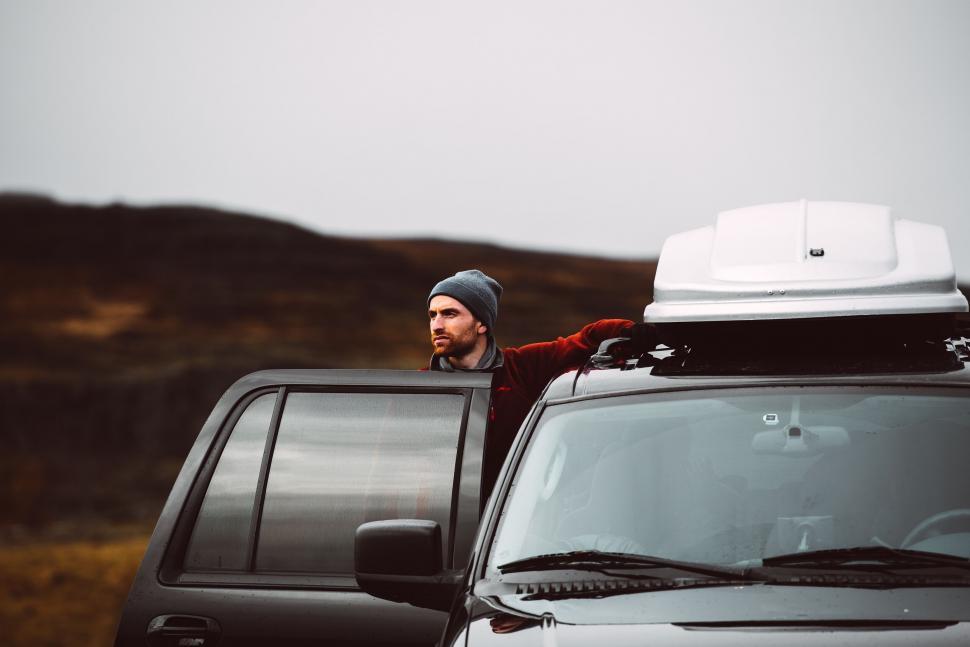 Free Image of Man leaning on SUV in rugged terrain 