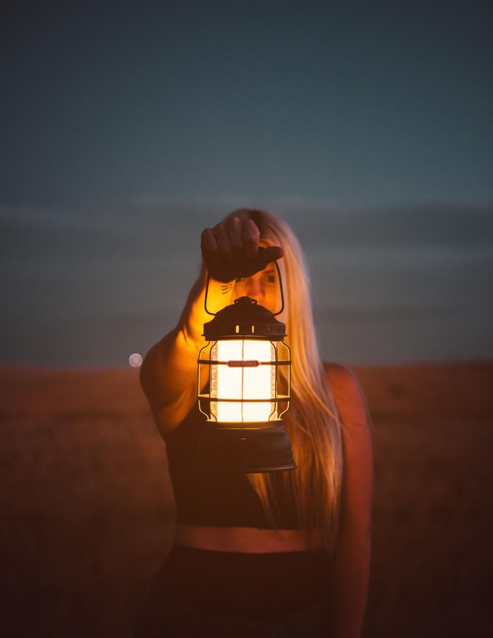 Free Image of Woman holding lantern in twilight field 
