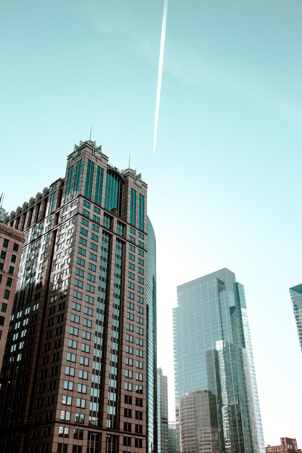 Free Image of Tall building with a jet trail in the sky 