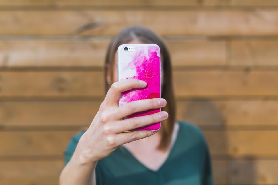 Free Image of Woman holding a pink object with blurred face 