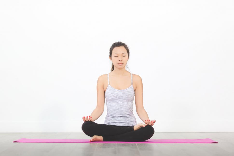 Free Image of Woman meditating on yoga mat in white space 