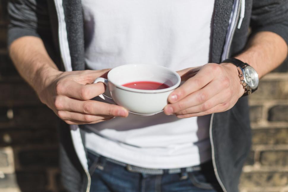 Free Image of Man holding a cup of red liquid 