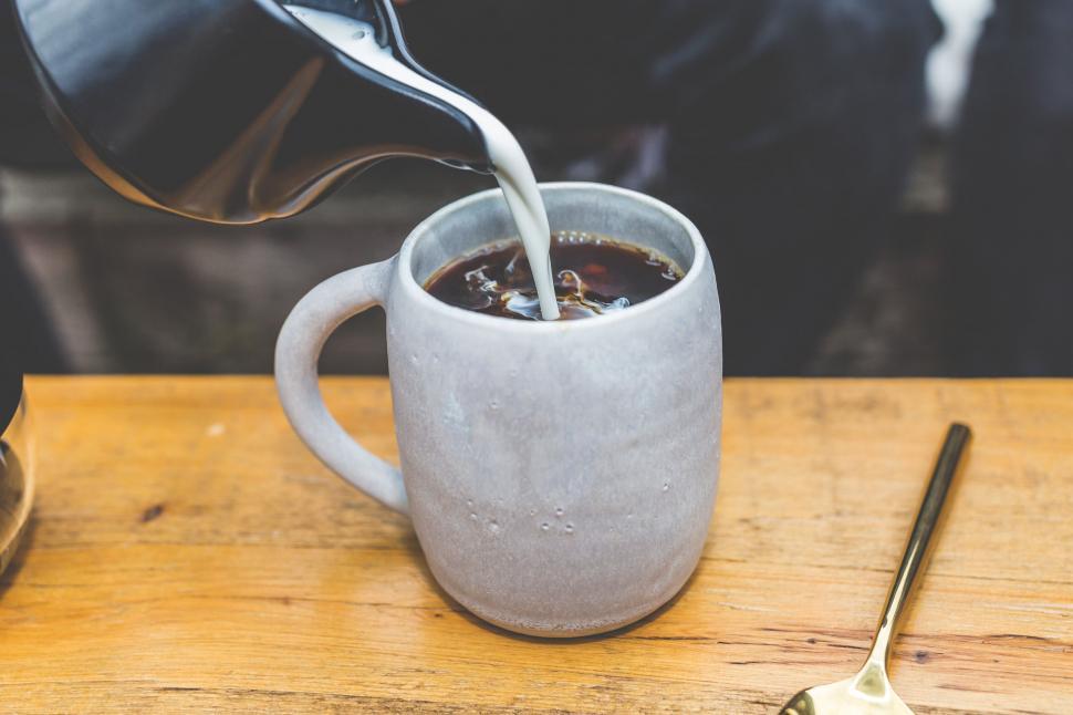 Free Image of Pouring milk into coffee in ceramic mug 