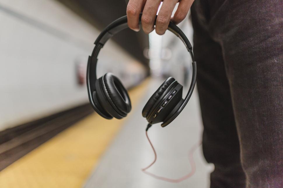 Free Image of Hand holding headphones in subway station 
