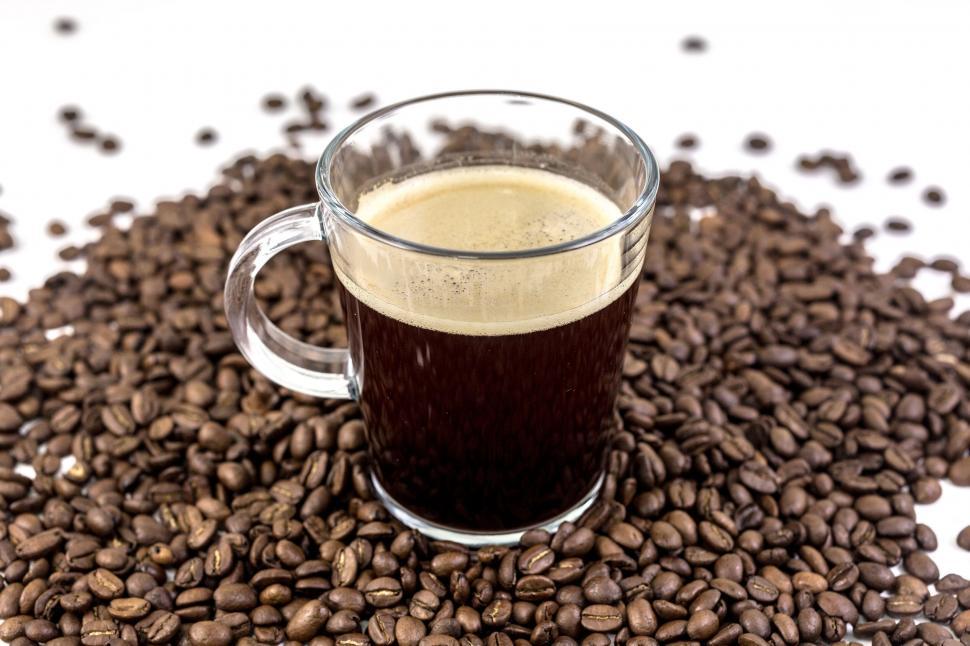 Free Image of Glass of coffee surrounded by coffee beans 