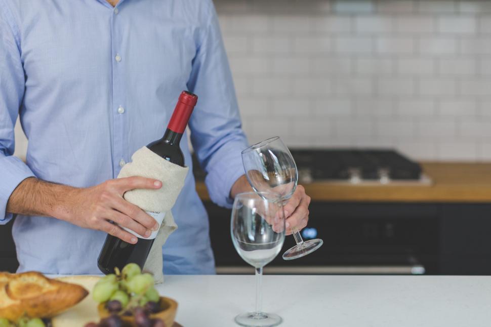 Free Image of Man pouring wine in modern kitchen setting 