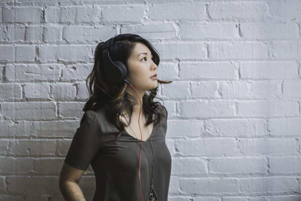 Free Image of Woman using headphones in front of a wall 