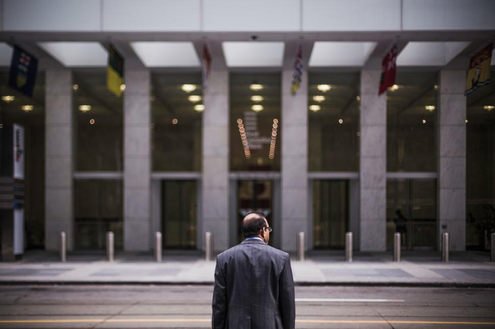 Free Image of Businessman in front of building with flags 