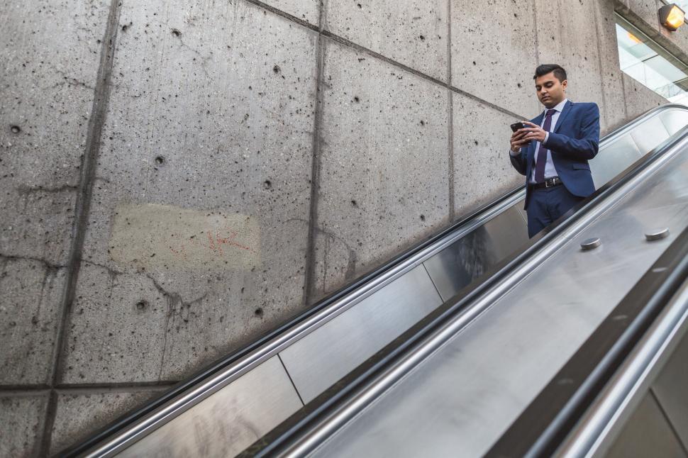 Free Image of Businessman using smartphone on escalator 