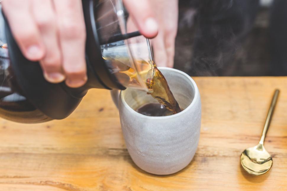 Free Image of Pouring hot coffee into a cup with steam rising 